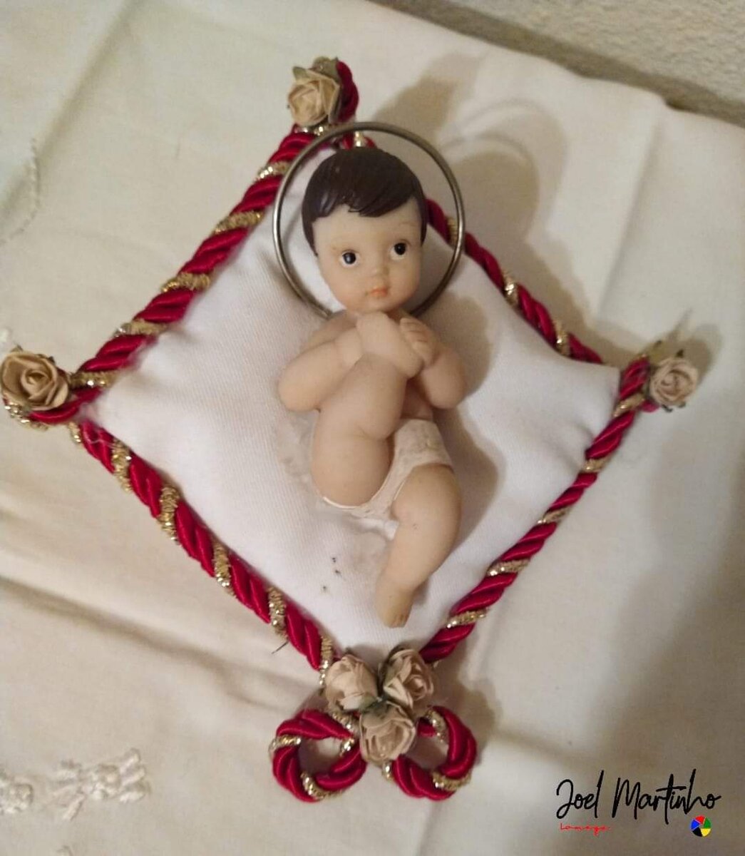 Menino Jesus em oração com auréola metálica sobre almofada com cordão vermelho