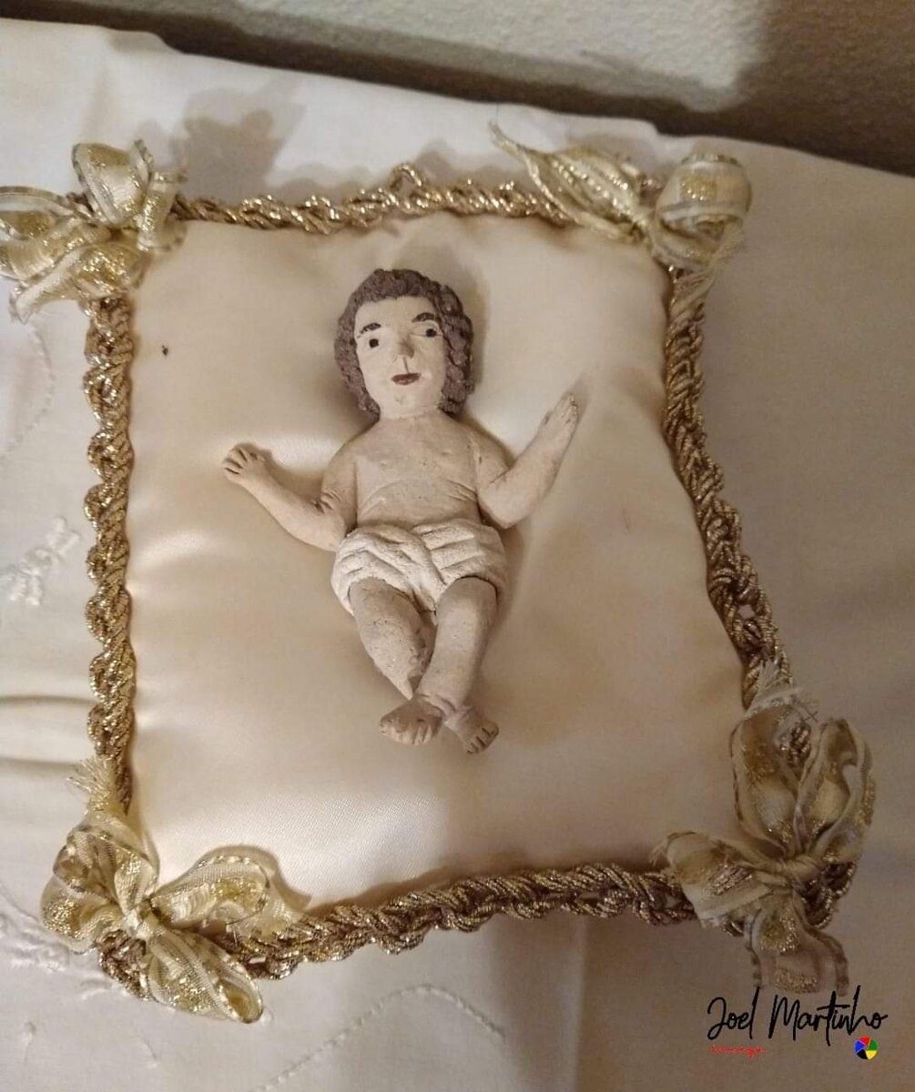 Pequeno Menino Jesus de feitura popular sobre almofada com galão dourado