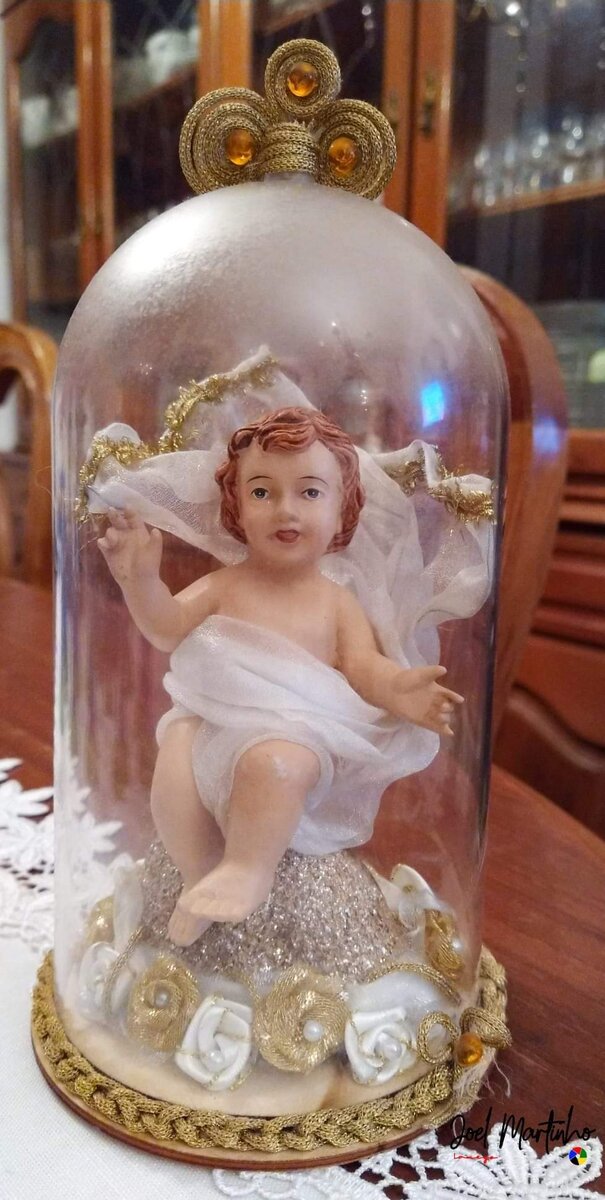 Menino Jesus sob redoma de vidro com base de rosas brancas e douradas