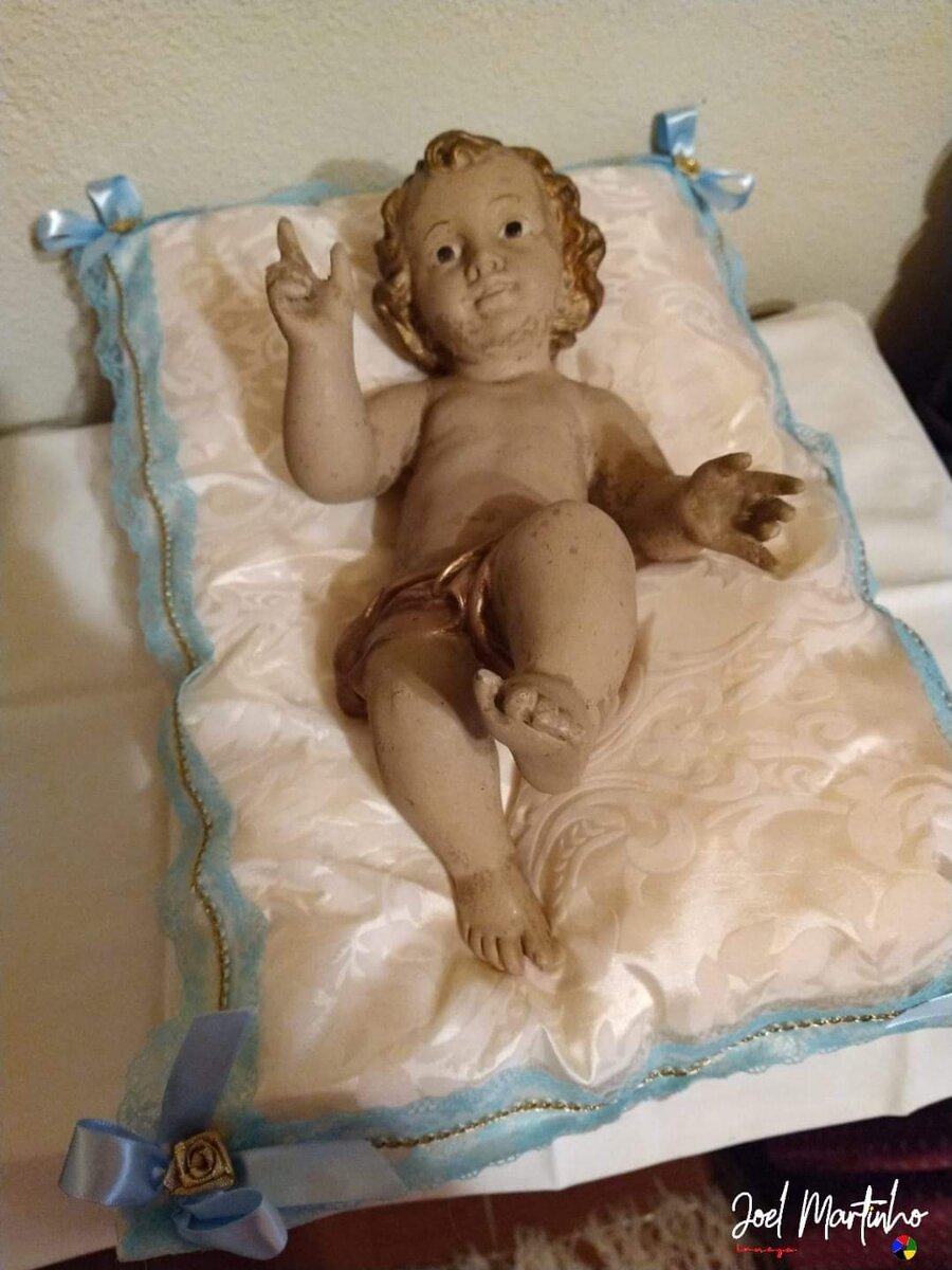 Menino Jesus com acabamento dourado sobre almofada creme com renda azul