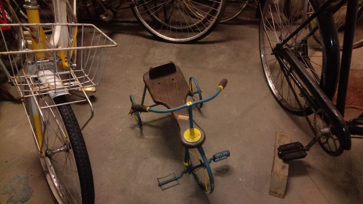 Triciclo infantil vintage com assento de madeira e estrutura azul e amarela